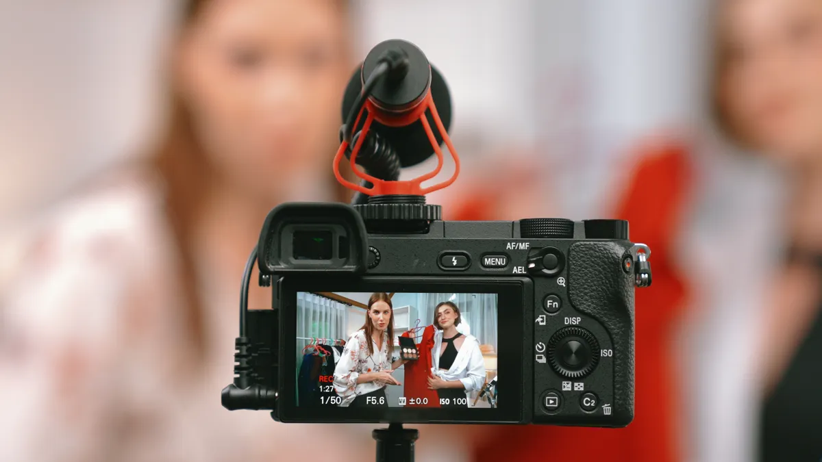 Two creators reviewing a dress and makeup on a camera screen during a shoot